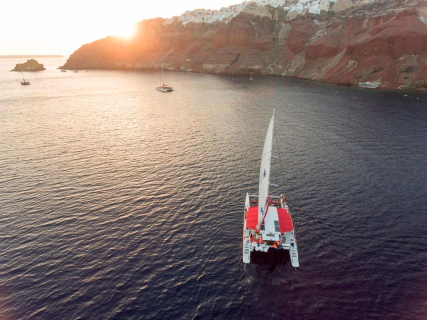Santorini: Cruise Catamaran with BBQ & Drinks Day or Sunset - Sailing beneath Fira and past the old port